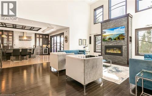 Living area with a glass covered fireplace, a high ceiling, dark wood finished floors, and wine cooler - 24 Jacob Gingrich Drive, Kitchener, ON - Indoor Photo Showing Other Room With Fireplace