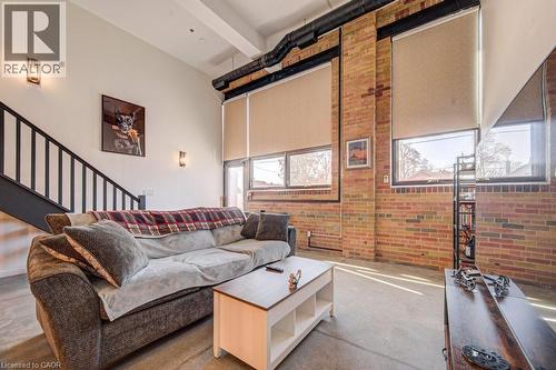 Living room with brick wall and stairway - 85 Spruce Street Unit# 103, Cambridge, ON - Indoor Photo Showing Living Room
