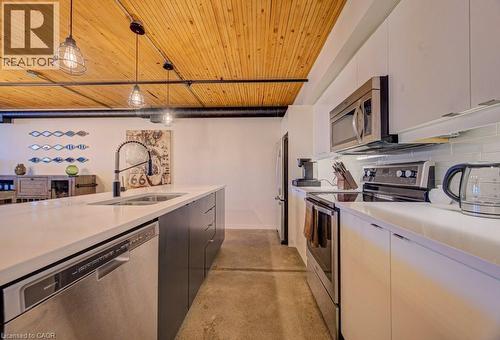 Dual tone kitchen with stainless steel appliances, finished concrete floors, pendant lighting, wooden ceiling, and backsplash - 85 Spruce Street Unit# 103, Cambridge, ON - Indoor Photo Showing Kitchen With Double Sink