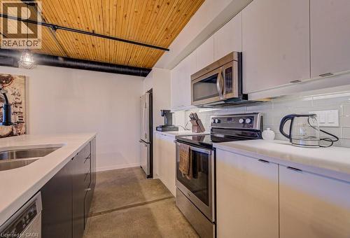 Kitchen featuring stainless steel appliances, wood ceiling, finished concrete floors, hanging light fixtures, and two tone cabinetry - 85 Spruce Street Unit# 103, Cambridge, ON - Indoor Photo Showing Kitchen With Stainless Steel Kitchen With Double Sink