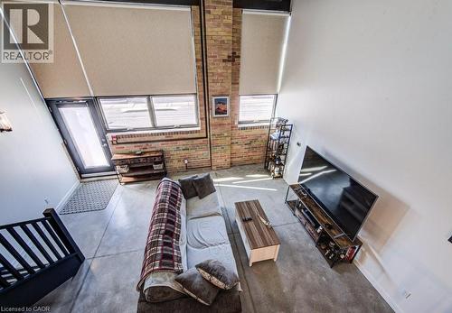 Living area featuring concrete floors, a high ceiling, plenty of natural light, and brick wall - 85 Spruce Street Unit# 103, Cambridge, ON - Indoor