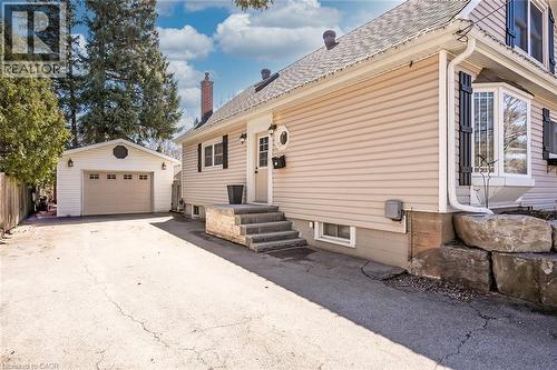 View of home's exterior featuring an outbuilding, a detached garage, driveway, and a shingled roof - 220 Townsend Avenue, Burlington, ON - Outdoor