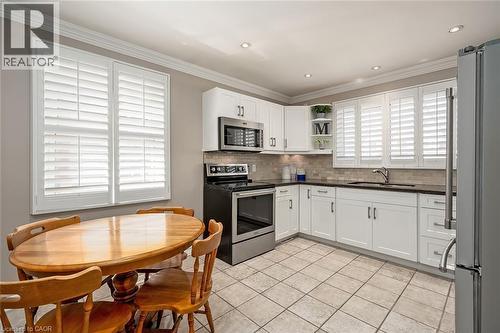 Kitchen with stainless steel appliances, open shelves, white cabinetry, tasteful backsplash, and light tile patterned flooring - 220 Townsend Avenue, Burlington, ON - Indoor