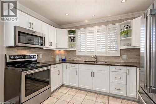 Kitchen featuring open shelves, stainless steel appliances, white cabinets, dark stone counters, and crown molding - 220 Townsend Avenue, Burlington, ON - Indoor Photo Showing Kitchen With Stainless Steel Kitchen With Double Sink
