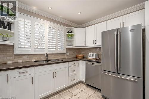 Kitchen with stainless steel appliances, open shelves, white cabinets, dark stone counters, and ornamental molding - 220 Townsend Avenue, Burlington, ON - Indoor Photo Showing Kitchen With Stainless Steel Kitchen With Double Sink