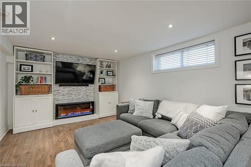 Living area featuring a large fireplace, wood finished floors, recessed lighting, and built in shelves - 220 Townsend Avenue, Burlington, ON - Indoor With Fireplace