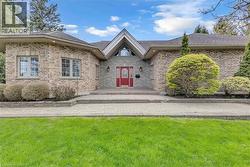 Brick exterior with a prominent red entry door and transom window, framed by a gabled portico - 