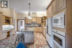 Kitchen featuring a breakfast bar, open shelves, white appliances, built in desk, and an island with sink - 