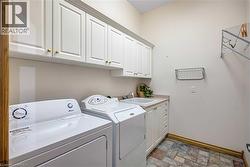 Laundry area featuring stone finish floors, cabinet space, and washing machine and dryer - 
