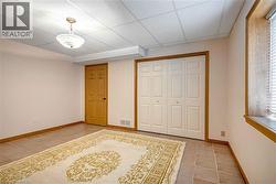 Unfurnished bedroom featuring a drop ceiling, light tile patterned floors, and a closet - 