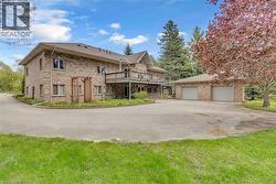 Brick exterior residence featuring a multi-level deck, an expansive paved driveway, and an attached two-car garage - 