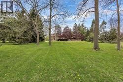 Expansive green lawn with mature trees and a gently sloping landscape towards the residence - 