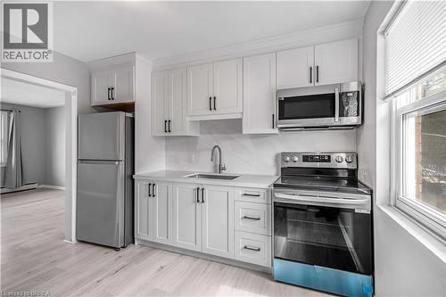 Kitchen featuring stainless steel appliances, white cabinets, light wood-type flooring, baseboard heating, and light stone countertops - 151 Siebert Avenue, Kitchener, ON - Indoor Photo Showing Kitchen