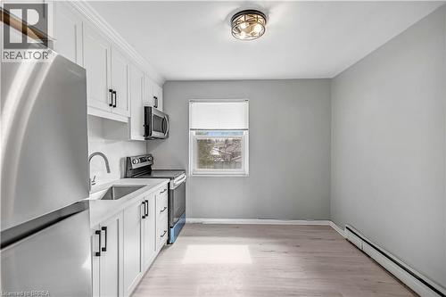 Kitchen featuring stainless steel appliances, white cabinets, baseboard heating, and light wood finished floors - 151 Siebert Avenue, Kitchener, ON - Indoor Photo Showing Kitchen