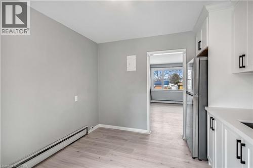 Kitchen featuring a baseboard heating unit, freestanding refrigerator, white cabinetry, light wood-style flooring, and a baseboard radiator - 151 Siebert Avenue, Kitchener, ON - Indoor