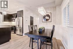 Dining area with suspended lighting, light wood-style flooring, a decorative wall, and wainscoting - 