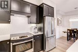 Kitchen featuring stainless steel appliances, light wood-style flooring, a wainscoted wall, a decorative wall, and light stone countertops - 