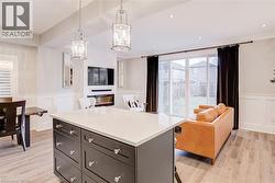 Kitchen featuring open floor plan, a wainscoted wall, a decorative wall, a kitchen island, and a kitchen breakfast bar - 