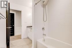 Bathroom featuring vanity, shower / washtub combination, and light wood-style floors - 