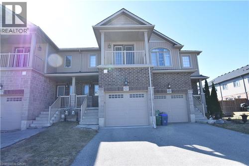 View of front of property with an attached garage, driveway, a balcony, covered porch, and brick siding - 52 Meadowridge Street, Kitchener, ON - Outdoor With Balcony With Facade