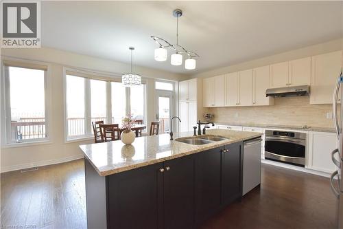 Kitchen with stainless steel appliances, light stone countertops, decorative backsplash, dark wood-style floors, and two tone cabinets - 512 Terrington Crescent, Kitchener, ON - Indoor Photo Showing Kitchen With Double Sink