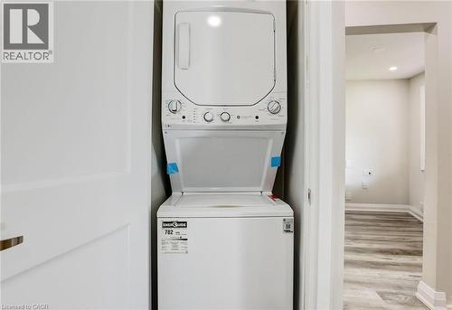 Laundry area featuring recessed lighting, stacked washing machine and dryer, and light wood finished floors - 7 Cardill Crescent, Waterloo, ON - Indoor Photo Showing Laundry Room