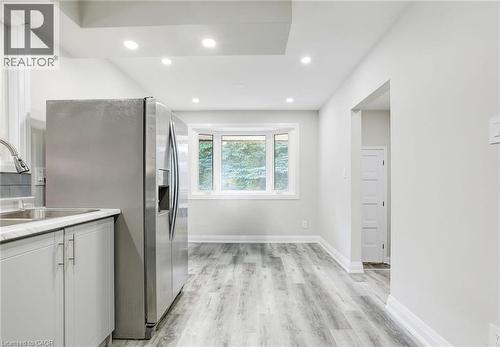 Kitchen with light countertops, stainless steel refrigerator with ice dispenser, light wood-style flooring, white cabinetry, and recessed lighting - 7 Cardill Crescent, Waterloo, ON - Indoor Photo Showing Kitchen With Double Sink