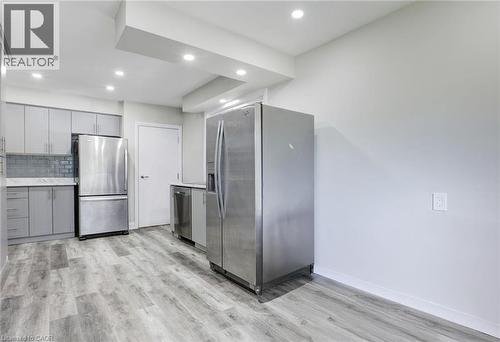 Kitchen featuring gray cabinets, stainless steel appliances, tasteful backsplash, light wood-style flooring, and recessed lighting - 7 Cardill Crescent, Waterloo, ON - Indoor Photo Showing Kitchen