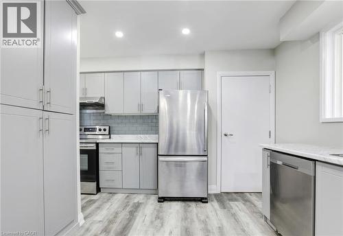 Kitchen with stainless steel appliances, light wood-style floors, tasteful backsplash, recessed lighting, and gray cabinetry - 7 Cardill Crescent, Waterloo, ON - Indoor Photo Showing Kitchen