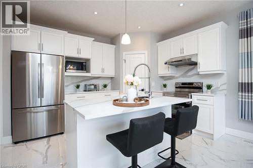Kitchen featuring stainless steel appliances, white cabinetry, light marble finish flooring, and a breakfast bar area - 346 Chokecherry Crescent, Waterloo, ON - Indoor Photo Showing Kitchen With Upgraded Kitchen