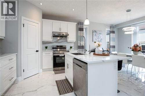 Kitchen with a kitchen island with sink, stainless steel appliances, white cabinets, light stone counters, and light marble finish floors - 346 Chokecherry Crescent, Waterloo, ON - Indoor Photo Showing Kitchen With Double Sink With Upgraded Kitchen
