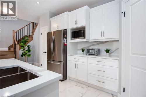 Kitchen featuring stainless steel appliances, white cabinets, light marble finish flooring, and light stone countertops - 346 Chokecherry Crescent, Waterloo, ON - Indoor Photo Showing Kitchen With Double Sink