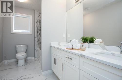 Full bath with double vanity, shower / tub combo, a textured ceiling, and light marble finish floors - 346 Chokecherry Crescent, Waterloo, ON - Indoor Photo Showing Bathroom
