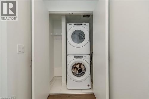 Laundry area with stacked washer / drying machine and light tile patterned flooring - 770 Whitlock Avenue Unit# 606, Milton, ON - Indoor Photo Showing Laundry Room