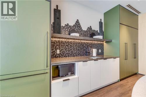 Kitchen featuring modern cabinets, paneled fridge, light wood-style flooring, and backsplash - 770 Whitlock Avenue Unit# 606, Milton, ON - Indoor Photo Showing Other Room