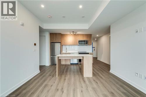 Kitchen featuring light countertops, stainless steel appliances, a center island, wood finish cabinetry, and tasteful backsplash - 770 Whitlock Avenue Unit# 606, Milton, ON - Indoor Photo Showing Kitchen