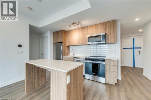 Kitchen with stainless steel appliances, a center island, light wood-type flooring, modern cabinets, and tasteful backsplash - 770 Whitlock Avenue Unit# 606, Milton, ON - Indoor Photo Showing Kitchen