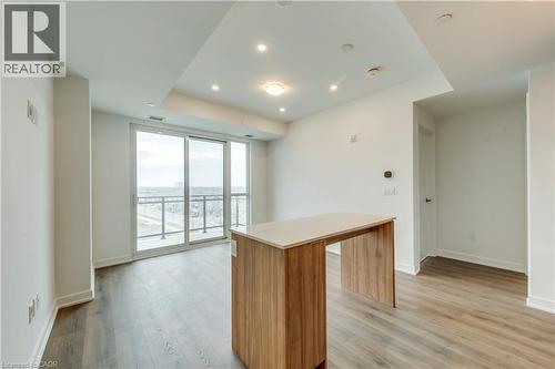Kitchen featuring light countertops, light wood-type flooring, a kitchen island, expansive windows, and wood finish cabinetry - 770 Whitlock Avenue Unit# 606, Milton, ON - Indoor Photo Showing Other Room