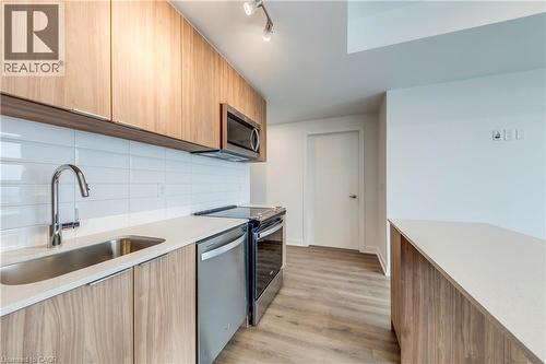 Kitchen with modern cabinets, light wood finish cabinetry, stainless steel appliances, light wood finished floors, and light stone countertops - 770 Whitlock Avenue Unit# 606, Milton, ON - Indoor Photo Showing Kitchen