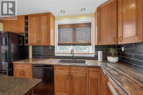 Kitchen with wood finish cabinets, black appliances, tasteful backsplash, recessed lighting, and dark stone counters - 703 Dunn Avenue, Hamilton, ON - Indoor Photo Showing Kitchen