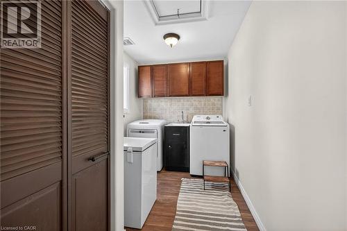 Laundry area featuring dark wood-style floors, cabinet space, and washer and dryer - 703 Dunn Avenue, Hamilton, ON - Indoor Photo Showing Laundry Room