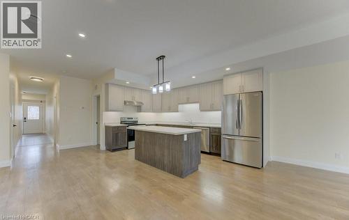 Kitchen with stainless steel appliances, light countertops, a center island, light wood finished floors, and dual tone cabinetry - 113 Walter Street, Kitchener, ON - Indoor Photo Showing Kitchen With Upgraded Kitchen