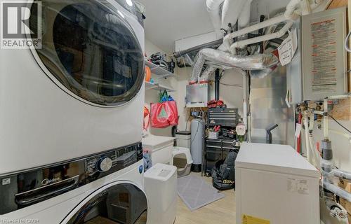 Laundry room with water heater, stacked washing machine and dryer, and light wood-style floors - 113 Walter Street, Kitchener, ON - Indoor Photo Showing Laundry Room