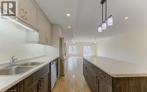 Kitchen featuring light countertops, light wood finished floors, a large island, stainless steel appliances, and hanging light fixtures - 113 Walter Street, Kitchener, ON - Indoor Photo Showing Kitchen With Double Sink