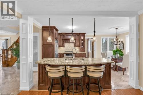 Kitchen featuring light stone counters, ornamental molding, a kitchen bar, light wood-style floors, and a center island with sink - 228 Michener Crescent, Kitchener, ON - Indoor Photo Showing Other Room