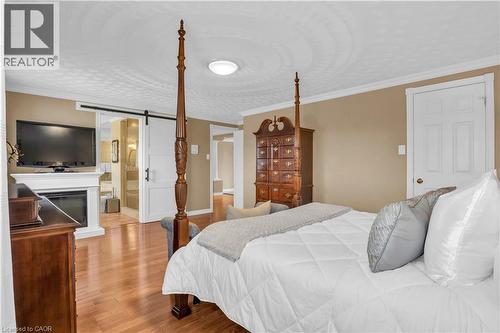 Bedroom with a barn door, crown molding, wood-type flooring, a glass covered fireplace, and connected bathroom - 228 Michener Crescent, Kitchener, ON - Indoor Photo Showing Bedroom