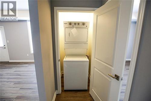 Laundry area with dark wood finished floors and stacked washer and clothes dryer - 40 Pietz Avenue, Welland, ON - Indoor Photo Showing Laundry Room
