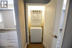 Laundry area with dark wood finished floors and stacked washer and clothes dryer - 