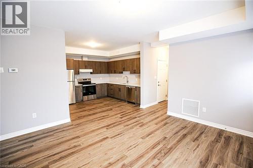 Kitchen with dark wood finish cabinets, stainless steel appliances, light countertops, light wood-type flooring, and open floor plan - 40 Pietz Avenue, Welland, ON - Indoor Photo Showing Kitchen