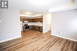 Kitchen with dark wood finish cabinets, stainless steel appliances, light countertops, light wood-type flooring, and open floor plan - 